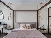 Modern bedroom with a canopy bed, decorative pillows, and wall lights, pink bed cover.